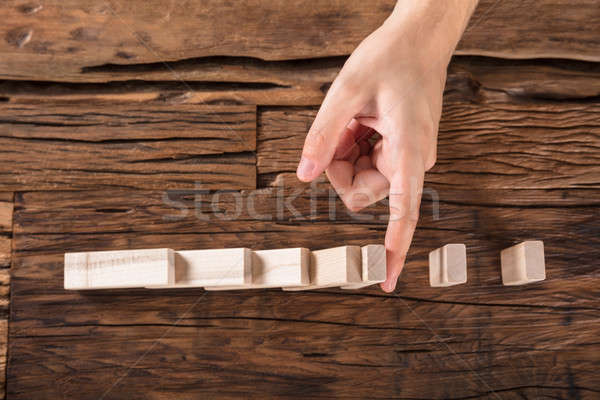 Person Stopping Dominoes To Continue Toppled At Desk Stock photo © AndreyPopov