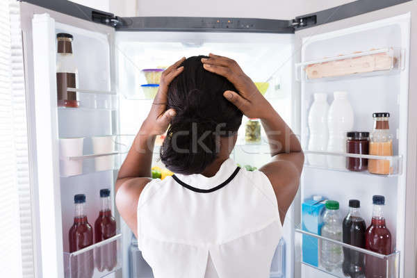 Confused Woman Looking In Open Refrigerator Stock photo © AndreyPopov