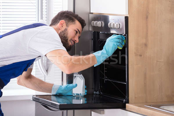 Woźny czyszczenia piekarnik kuchnia szczęśliwy mężczyzna Zdjęcia stock © AndreyPopov