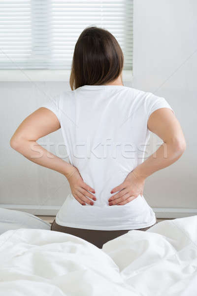 Femeie dureri de spate şedinţei pat cameră Imagine de stoc © AndreyPopov