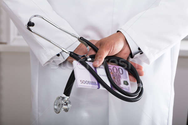 Doctor holding stethoscope and banknotes Stock photo © AndreyPopov
