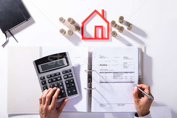 Businessman Calculating Bill In Front Of Coins And House Model Stock photo © AndreyPopov