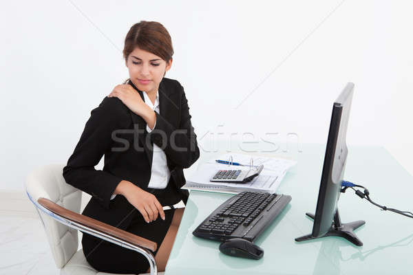 Businesswoman Having Shoulder Pain At Computer Desk Stock photo © AndreyPopov