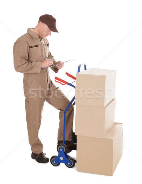 Delivery Man Writing On Clipboard By Cart And Cardboard Boxes Stock photo © AndreyPopov