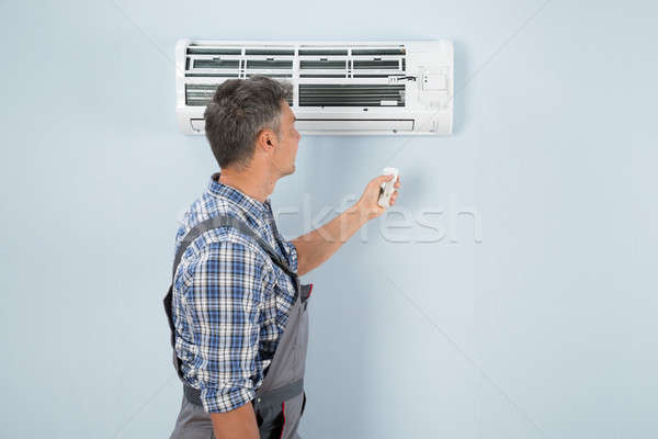 Repairman Operating Air Conditioner With Remote Controller Stock photo © AndreyPopov