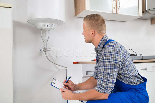 Plumber With Clipboard In Front Of Electric Boiler Stock photo © AndreyPopov
