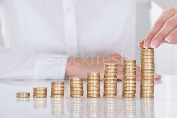 Businesswoman Hand Placing Coin Over Stack Of Coins Stock photo © AndreyPopov