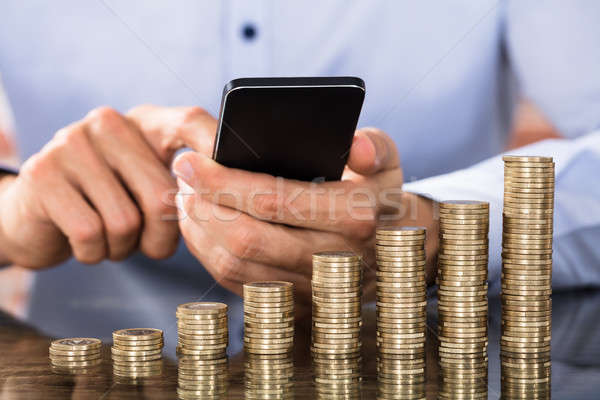 Businessman Using Smart Phone For Calculating Coins Stock photo © AndreyPopov