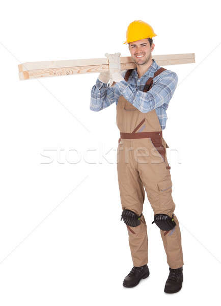 Worker wearing hard hat and carrying timber Stock photo © AndreyPopov