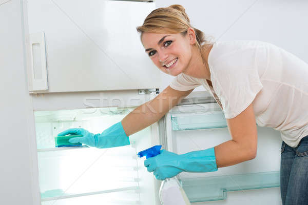 Mujer sonriente limpieza refrigerador esponja aerosol retrato Foto stock © AndreyPopov