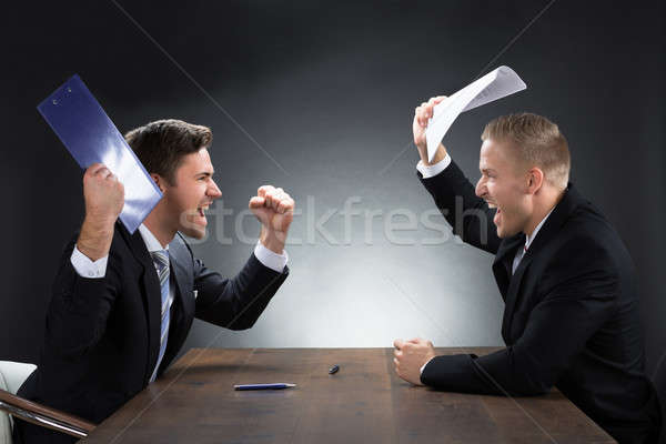 Aggressive Young Businessmen Arguing At Desk Stock photo © AndreyPopov