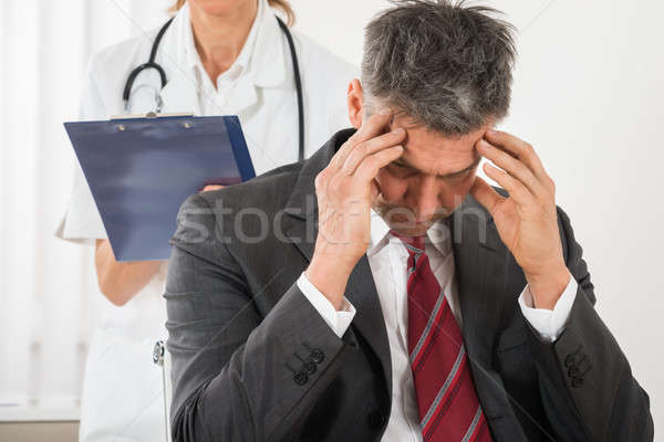 Doctor Standing Behind The Businessman Having Headache Stock photo © AndreyPopov