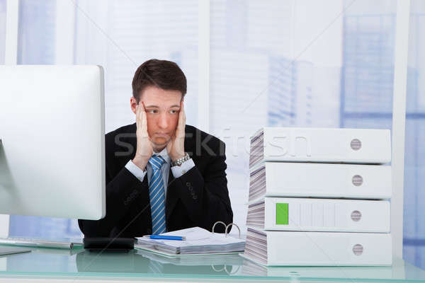 Worried Businessman Looking At Binders On Desk Stock photo © AndreyPopov