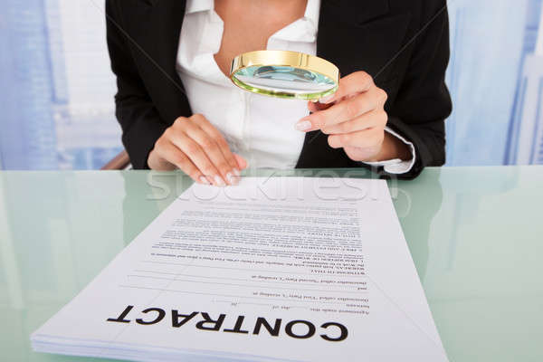 Businesswoman Scrutinizing Contract With Magnifying Glass Stock photo © AndreyPopov