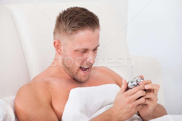Stock photo: Man screaming in frustration at his alarm clock