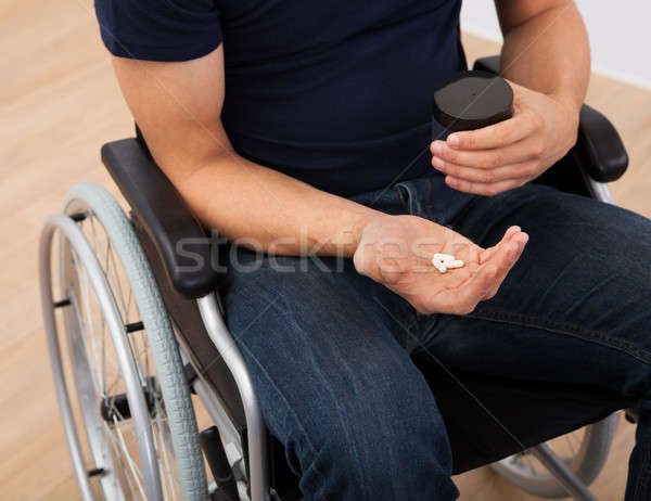 Man Holding Medicine While Sitting On Wheelchair Stock photo © AndreyPopov