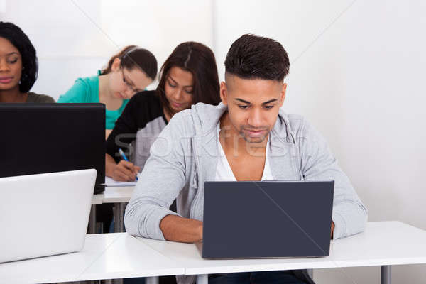 Egyetemi hallgató laptopot használ asztal férfi osztálytársak számítógép Stock fotó © AndreyPopov