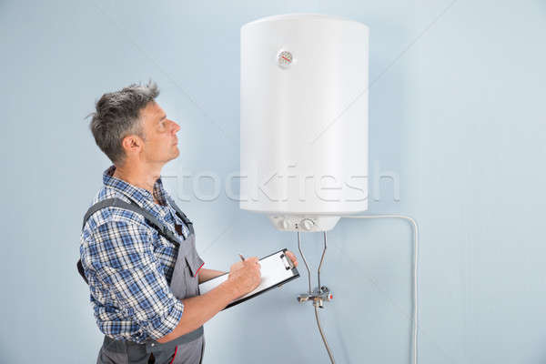 Male Plumber With Clipboard Looking At Electric Boiler Stock photo © AndreyPopov