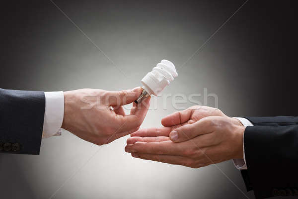 Businessperson Hand Offering Light Bulb To Other Businessperson Stock photo © AndreyPopov
