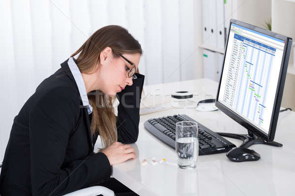 Businesswoman With Pills And Glass Of Water At Desk Stock photo © AndreyPopov