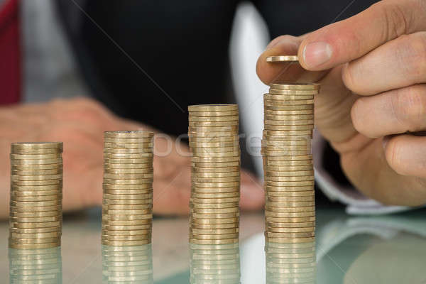 Businessman Placing Coin Over Stack Of Coins At Desk Stock photo © AndreyPopov