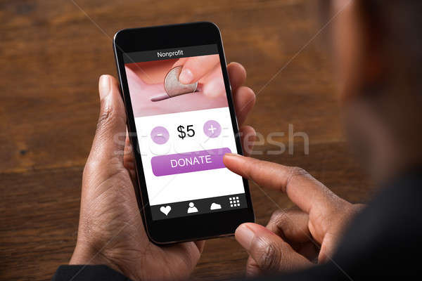 African Business Man Holding Mobile Phone Donating Money Stock photo © AndreyPopov