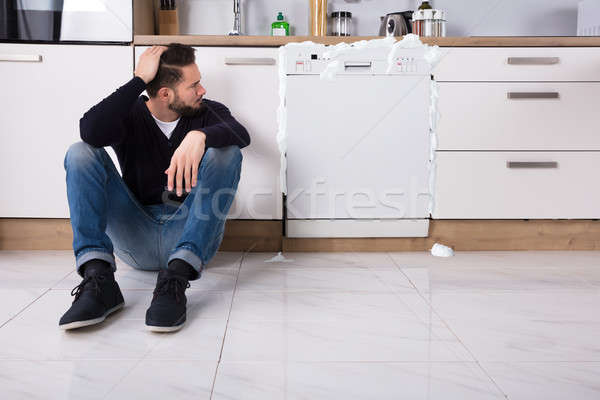 Sconvolto uomo seduta lavastoviglie schiuma fuori Foto d'archivio © AndreyPopov