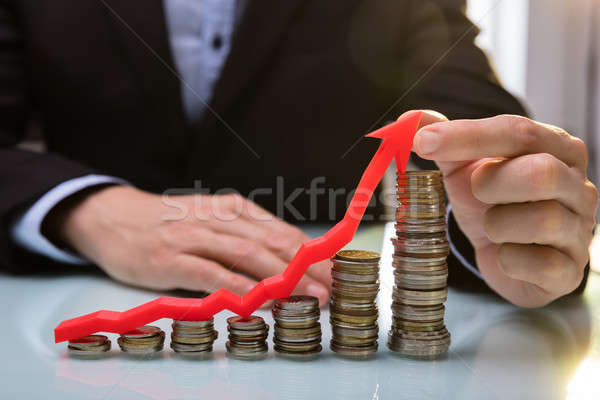 Businessperson Holding Arrow Over Increasing Stacked Coins Stock photo © AndreyPopov