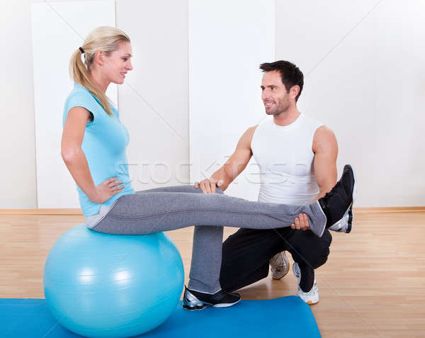 Instructor helping a woman with pilates exercises Stock photo © AndreyPopov