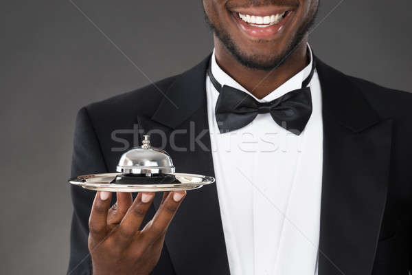 African Waiter Holding Service Bell Stock photo © AndreyPopov