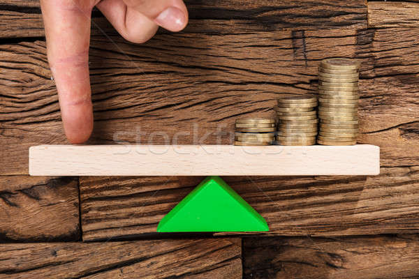Stock photo: Finger Balancing Stacked Coins On Seesaw