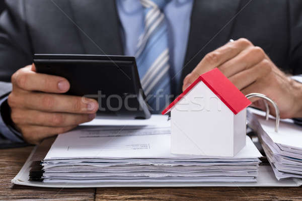 Businessman Calculating Invoice With Model Home On Documents Stock photo © AndreyPopov