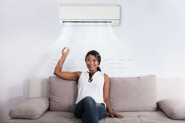 Woman Using Air Conditioner At Home Stock photo © AndreyPopov