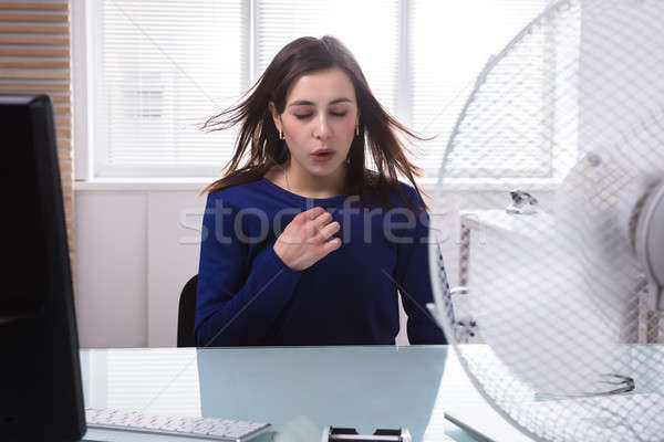 Businesswoman Enjoying Breeze With Electric Fan Stock photo © AndreyPopov