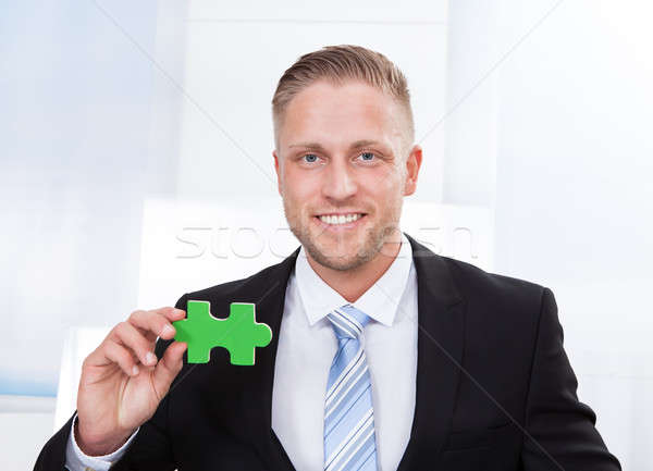 Successful businessman holding a puzzle piece Stock photo © AndreyPopov
