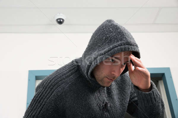 Man In Hooded Sweatshirt With Cctv Camera Behind Stock photo © AndreyPopov