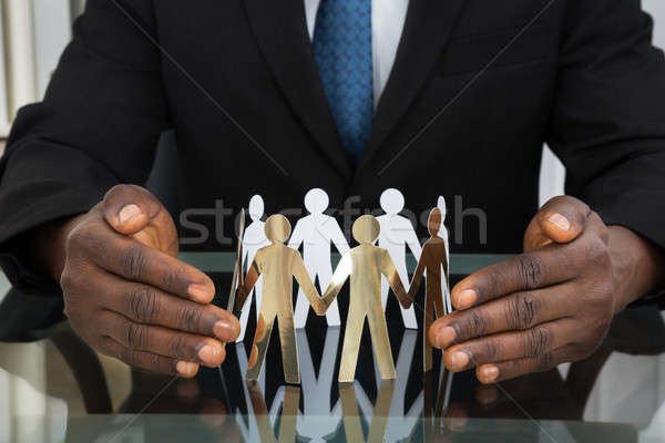 Businessman Protecting Paper Cutout People Stock photo © AndreyPopov