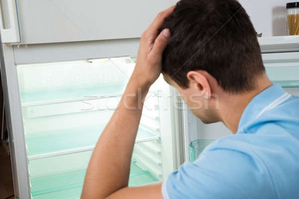 Confused Man Scratching Head While Looking At Empty Refrigerator Stock photo © AndreyPopov