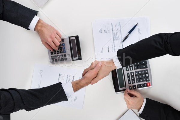 Stock photo: Businessmen Shaking Hands While Calculating Finance At Desk