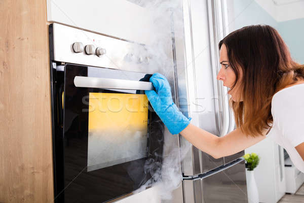 Woman Looking At Smoke Coming Out Of Oven Stock photo © AndreyPopov