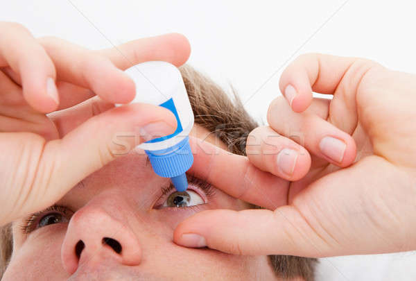 Stock photo: Man pouring drops in her eyes