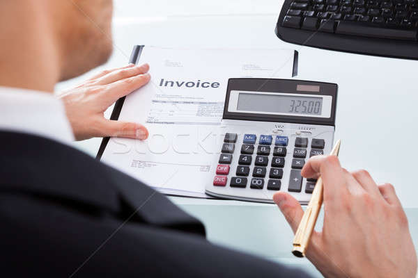 Businessman Calculating Invoice At Office Desk Stock photo © AndreyPopov