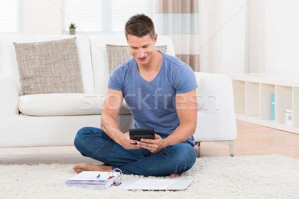 Hombre presupuesto calculadora joven sesión alfombra Foto stock © AndreyPopov