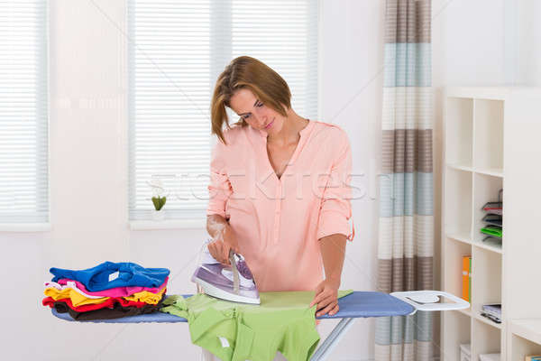 Happy Woman Ironing Cloth With Electric Iron In Kitchen Stock