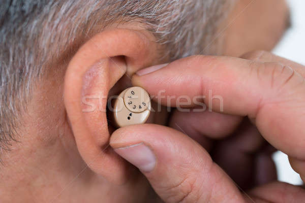 Closeup Of Businessman Inserting Hearing Aid In Ear Stock photo © AndreyPopov