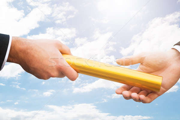 Person Passing Golden Relay Baton To Another Person Stock photo © AndreyPopov