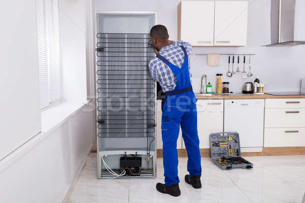 Serviceman In Overall Working On Fridge Stock photo © AndreyPopov