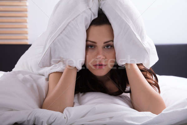 Woman On Bed Covering Her Ear With Bedsheet Stock photo © AndreyPopov