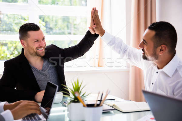 Dois empresários high five sorridente jovem escritório Foto stock © AndreyPopov