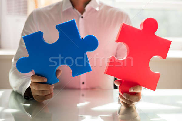 Businessman connecting two jigsaw puzzles Stock photo © AndreyPopov